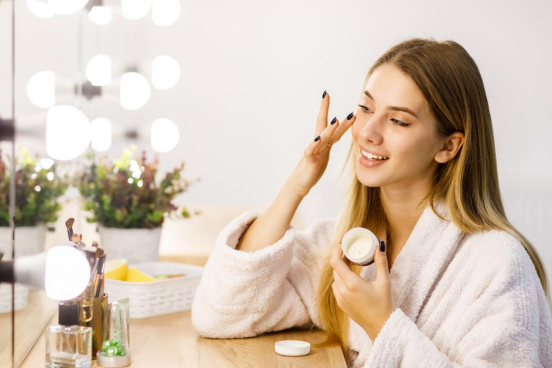 A beautiful woman sitting at the dressing table applying skin care products A beautiful woman sitting at the dressing table applying skin care products